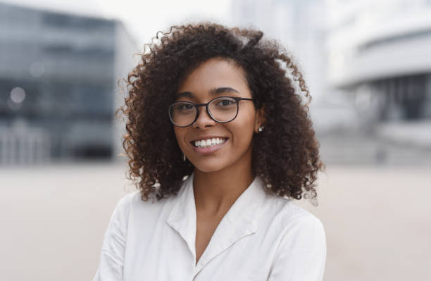 Smiling african-american businesswoman in a city. Mixed race girl looking at camera. People, city life, student lifestyle concept